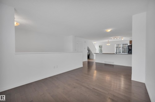 Open-concept living area featuring wood-finish flooring, white walls, and contemporary ceiling lighting - 13 1030 Chappelle Boulevard, Edmonton, AB - Indoor Photo Showing Other Room
