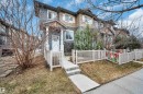 Multi-level townhouse exterior featuring a covered entry, white picket fencing, and a concrete walkway - 13 1030 Chappelle Boulevard, Edmonton, AB  - Outdoor 