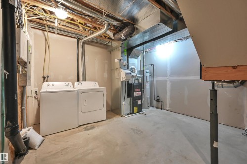 Utility space featuring a washer and dryer, exposed ceiling joists, ductwork, and a water heater - 13 1030 Chappelle Boulevard, Edmonton, AB - Indoor Photo Showing Laundry Room