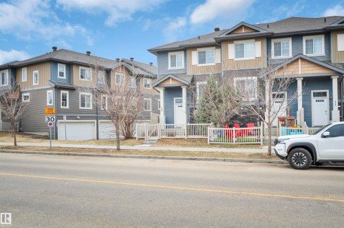 Multi-story townhome with distinct siding colors and a white picket fence - 13 1030 Chappelle Boulevard, Edmonton, AB - Outdoor With Facade