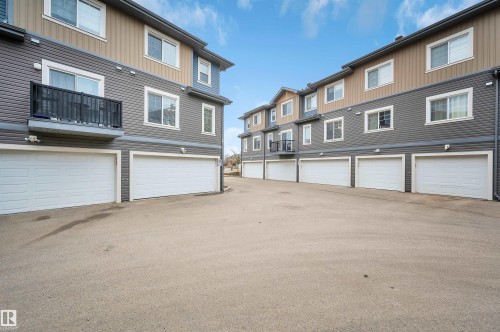Multi-story residential buildings featuring garages with white doors and gray siding accents - 13 1030 Chappelle Boulevard, Edmonton, AB - Outdoor