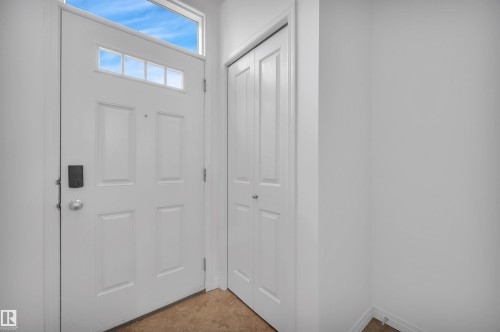 Entryway featuring a paneled door with transom window and sidelight, wood-finish flooring, white walls, and a bi-fold closet - 13 1030 Chappelle Boulevard, Edmonton, AB - Indoor Photo Showing Other Room