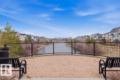 Paved patio featuring a circular brick pattern, metal railing, and direct water access - 18, 2560 Pegasus Boulevard, Edmonton, AB - Outdoor