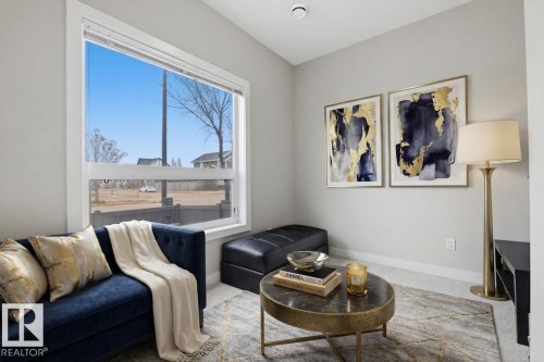 Bright living area featuring a large picture window, light gray wall paint, and gray carpeting - 18, 2560 Pegasus Boulevard, Edmonton, AB - Indoor