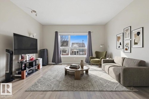 Bright living space featuring wood-finish flooring and neutral wall tones - 18, 2560 Pegasus Boulevard, Edmonton, AB - Indoor Photo Showing Living Room