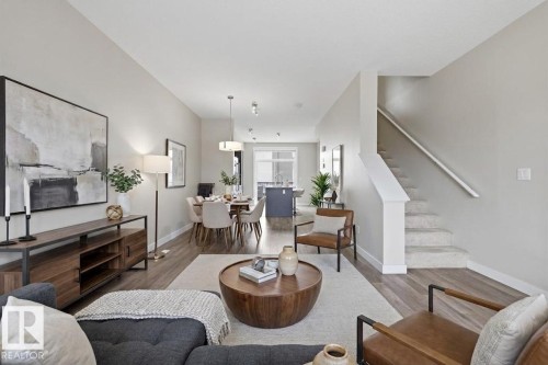 Open-concept living area with wood-finish flooring, light grey walls, and a carpeted staircase - 18, 2560 Pegasus Boulevard, Edmonton, AB - Indoor Photo Showing Living Room