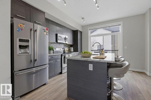Modern kitchen featuring wood-finish flooring and track lighting - 18, 2560 Pegasus Boulevard, Edmonton, AB - Indoor Photo Showing Kitchen