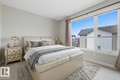 Spacious bedroom featuring large windows, light gray walls, and soft carpet flooring - 18, 2560 Pegasus Boulevard, Edmonton, AB - Indoor Photo Showing Bedroom