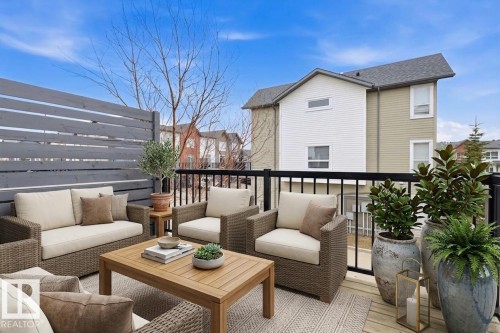 Spacious outdoor deck featuring wood-finish flooring, a modern privacy fence, and black metal railings - 18, 2560 Pegasus Boulevard, Edmonton, AB - Outdoor With Deck Patio Veranda With Exterior