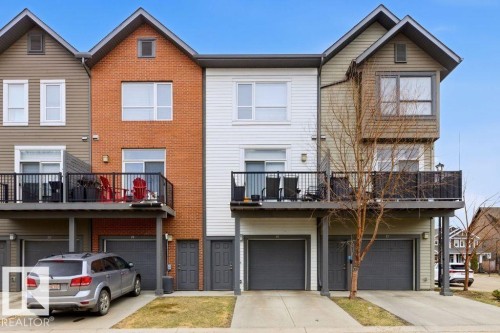 Multi-level townhouse exterior featuring a brick facade, white siding, and horizontal paneling - 18, 2560 Pegasus Boulevard, Edmonton, AB - Outdoor With Facade