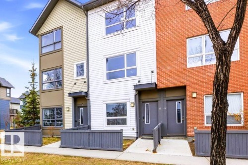 Multi-level townhome exterior featuring an entrance with an awning and a grey fence - 18, 2560 Pegasus Boulevard, Edmonton, AB - Outdoor With Facade