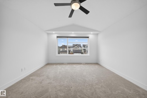 Spacious room with a large window, plush carpet flooring, recessed lighting, and a contemporary ceiling fan - 7414 Chivers Crescent Sw, Edmonton, AB - Indoor