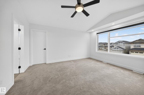 Spacious interior room featuring a large horizontal window, sloped ceiling, recessed lighting, and a ceiling fan with integrated light - 7414 Chivers Crescent Sw, Edmonton, AB - Indoor Photo Showing Other Room