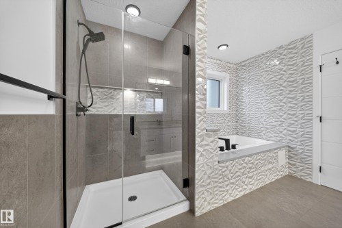 Modern bathroom featuring a tiled shower with a clear glass enclosure and matte black fixtures - 7414 Chivers Crescent Sw, Edmonton, AB - Indoor Photo Showing Bathroom