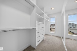 Custom white closet system featuring shelving, hanging rods, and built-in drawers with matte black hardware - 