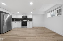 Contemporary kitchen featuring white cabinetry and stainless steel appliances - 