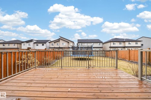 Expansive wood deck with metal railings overlooking a backyard with a grass lawn and wood fencing - 7414 Chivers Crescent Sw, Edmonton, AB - Outdoor With Deck Patio Veranda With Exterior