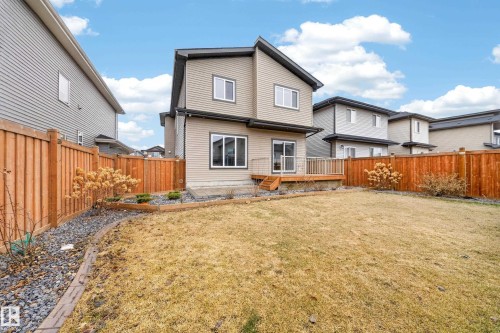 Expansive backyard featuring a wooden deck with railing, sliding glass door access, and a full privacy fence - 7414 Chivers Crescent Sw, Edmonton, AB - Outdoor With Deck Patio Veranda
