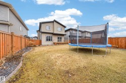 Expansive backyard featuring a manicured lawn, established wooden fencing, and a decorative rock border - 