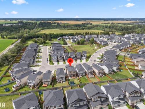 Aerial perspective showcasing a residential neighborhood with detached homes, surrounded by green spaces and agricultural fields - 7414 Chivers Crescent Sw, Edmonton, AB - Outdoor With View