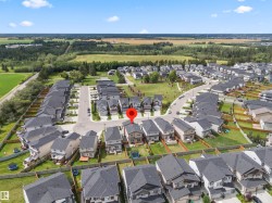 Aerial perspective showcasing a residential neighborhood with detached homes, surrounded by green spaces and agricultural fields - 