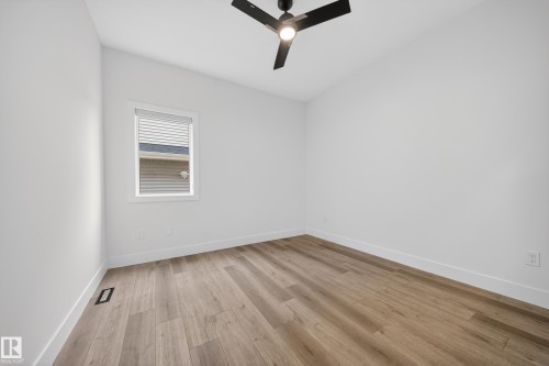 Room featuring light wood-finish flooring, white walls, and a contemporary black ceiling fan with integrated lighting - 7414 Chivers Crescent Sw, Edmonton, AB - Indoor Photo Showing Other Room