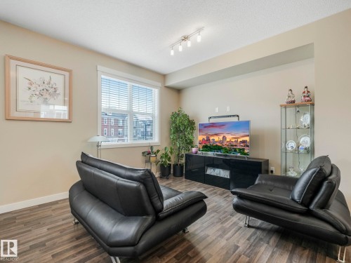 Living area featuring durable wood-finish flooring, neutral-toned walls, and a recessed ceiling alcove - 96 8315 180 Avenue, Edmonton, AB - Indoor Photo Showing Other Room