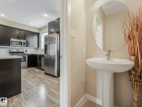 Pedestal sink with a circular mirror - 96 8315 180 Avenue, Edmonton, AB - Indoor Photo Showing Kitchen