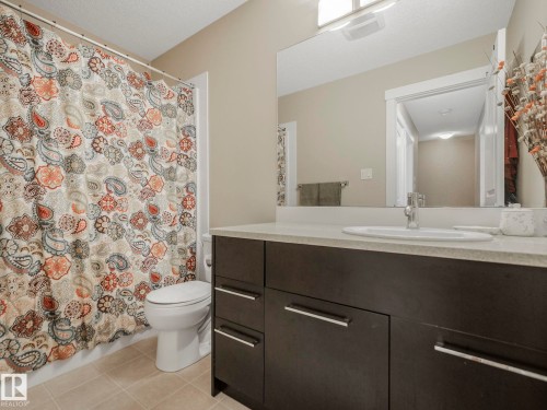 Bathroom vanity with dark wood-finish cabinetry, a light-toned countertop, and an integrated rectangular sink - 96 8315 180 Avenue, Edmonton, AB - Indoor Photo Showing Bathroom