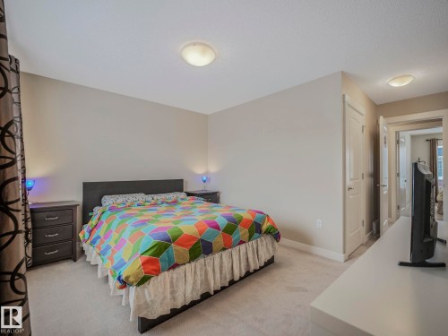 Carpeted bedroom featuring light neutral wall paint, a flush-mount ceiling light fixture, and white trim - 96 8315 180 Avenue, Edmonton, AB - Indoor Photo Showing Bedroom