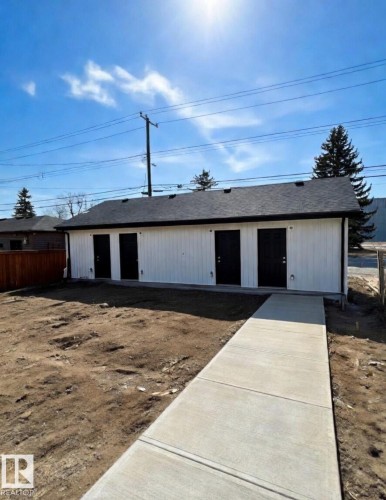The property features a white exterior with a dark roof and four dark entry doors - 11327 122 St, Edmonton, AB - Outdoor