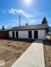 The property features a white exterior with a dark roof and four dark entry doors - 11327 122 St, Edmonton, AB  - Outdoor 