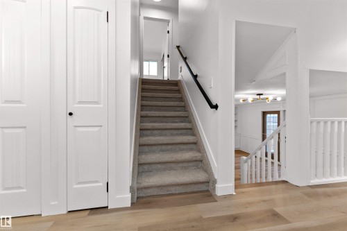 Carpeted staircase featuring a black handrail and white balusters - 3208 130 Avenue, Edmonton, AB - Indoor Photo Showing Other Room