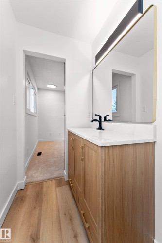 Modern vanity featuring wood-finish cabinetry, a white countertop, and a matte black faucet - 3208 130 Avenue, Edmonton, AB - Indoor Photo Showing Other Room