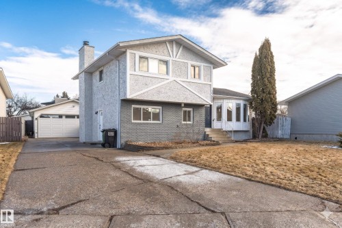 Two-story stucco exterior with decorative gables, a lower-level gray brick facade, and a prominent chimney - 3208 130 Avenue, Edmonton, AB - Outdoor