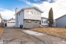 Two-story stucco exterior with decorative gables, a lower-level gray brick facade, and a prominent chimney - 3208 130 Avenue, Edmonton, AB  - Outdoor 