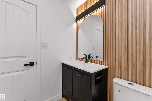 Contemporary bathroom vanity featuring a dark wood-finish cabinet, white countertop with integrated sink, and matte black faucet - 3208 130 Avenue, Edmonton, AB - Indoor Photo Showing Bathroom