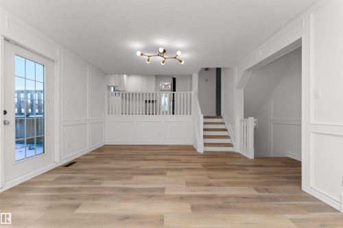 Spacious open-concept room featuring light wood-finish flooring and white wainscoting - 3208 130 Avenue, Edmonton, AB - Indoor Photo Showing Other Room