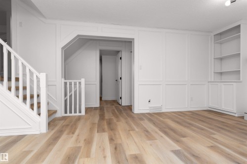 Light wood-finish flooring extending throughout, complemented by crisp white wainscoting and trim - 3208 130 Avenue, Edmonton, AB - Indoor Photo Showing Other Room