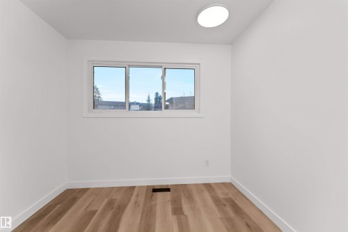 Bright interior space featuring a double-pane window, wood-finish flooring, white baseboards, and a flush-mount ceiling light - 3208 130 Avenue, Edmonton, AB - Indoor Photo Showing Other Room