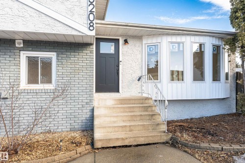 Exterior featuring a dark gray front door, concrete steps with a metal handrail, and a bay window with vertical paneling - 3208 130 Avenue, Edmonton, AB - Outdoor