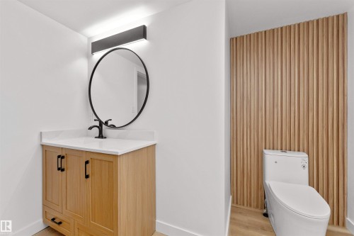 Bathroom featuring a wood-finish vanity with black hardware, a white countertop, and a black oval mirror - 3208 130 Avenue, Edmonton, AB - Indoor Photo Showing Other Room