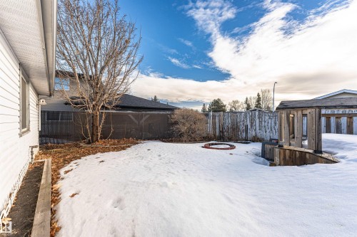Spacious rear yard featuring an open snow-covered lawn, a wood fence perimeter, and a built-in wood-clad structure - 3208 130 Avenue, Edmonton, AB - Outdoor
