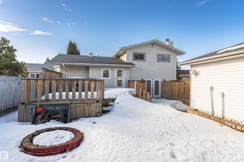 Expansive backyard featuring a wood deck with railings, a brick fire pit, and a separate detached structure with white siding - 3208 130 Avenue, Edmonton, AB - Outdoor With Deck Patio Veranda With Exterior