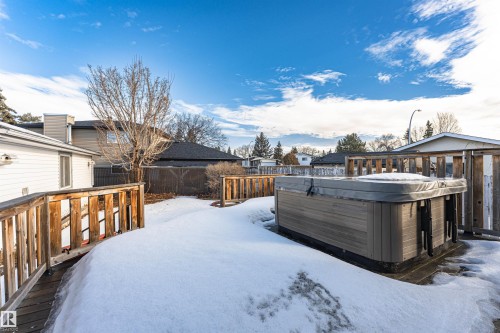 Backyard featuring a hot tub on a multi-level wood deck, with wood fencing and mature trees - 3208 130 Avenue, Edmonton, AB - Outdoor