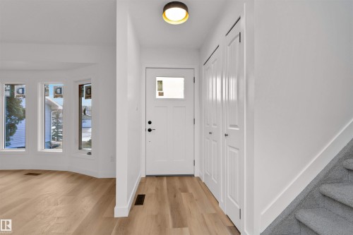 Entryway featuring a white paneled door with window insert, overhead flush mount lighting, light wood-finish flooring, and built-in closet storage - 3208 130 Avenue, Edmonton, AB - Indoor Photo Showing Other Room