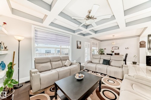 Living area featuring a coffered ceiling with a ceiling fan, recessed lighting, and a large window with blinds - 69 Caragana Way, Fort Saskatchewan, AB 