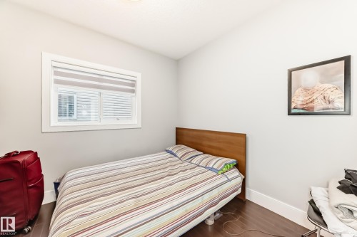 Room featuring wood-finish flooring, a window with horizontal blinds, light-toned walls, and white baseboards - 69 Caragana Way, Fort Saskatchewan, AB 