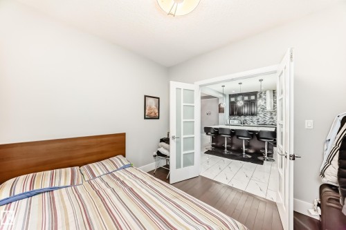 Double French doors opening to a contemporary kitchen with dark wood-finish cabinetry, a white countertop, and a tiled backsplash - 69 Caragana Way, Fort Saskatchewan, AB 
