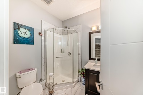 Corner glass shower enclosure with white base and marble-look wall tiling - 69 Caragana Way, Fort Saskatchewan, AB 